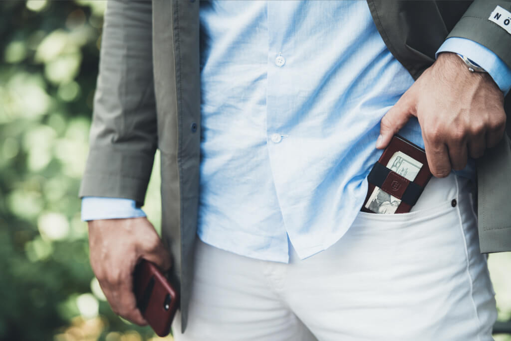 Image of a man sliding an Ekster smart wallet into his pocket. His other pocket holds an iPhone with an Ekster case.