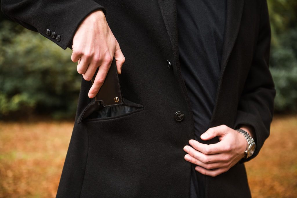 Person putting a card wallet into their coat pocket
