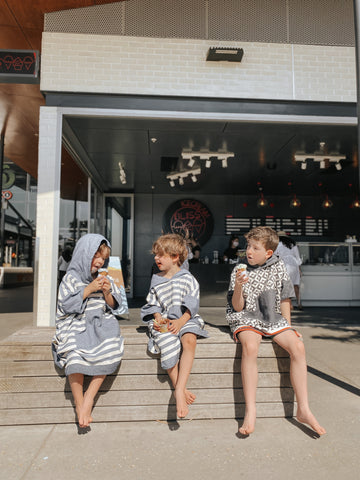 Three kids having ice cream with their Blem Surf Ponchos