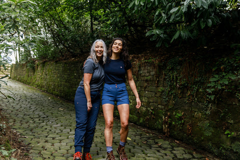 Two women walking down a cobbled road together wearing the Merino Wool T-shirt, Trek Shorts, Casual Stroll Trousers