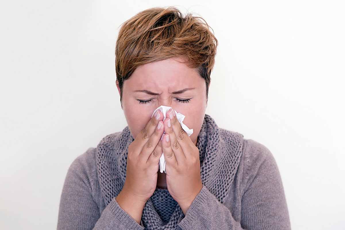 Woman sneezing into tissue