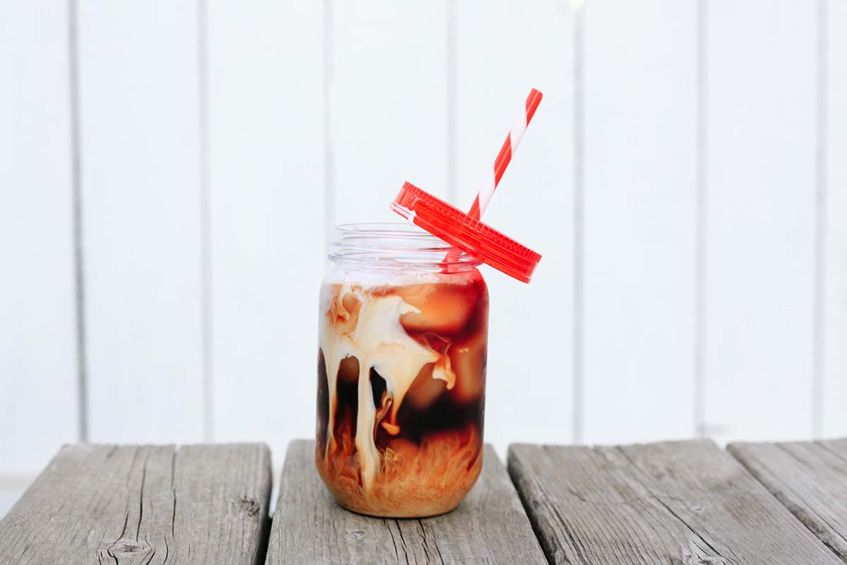 Iced coffee with red and white straw on table