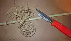 A survival knife scarping an arrow shaft