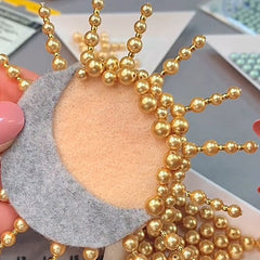 Sew gold pearls on to the sun - brooch jewellery project