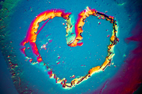 The surface etching on this colorless beryl resembles a heart. Differential interference contrast microscopy shows the details of the etching in vibrantly colored, high contrast. Field of View: 1.1mm