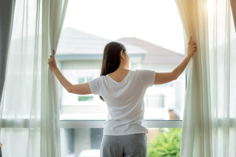 woman-waking-up-her-bed-fully-rested-opening-window-curtains
