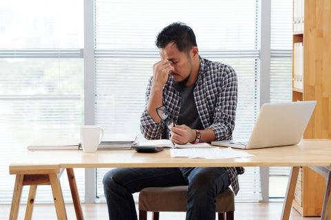 stressed man sitting with laptop and documents