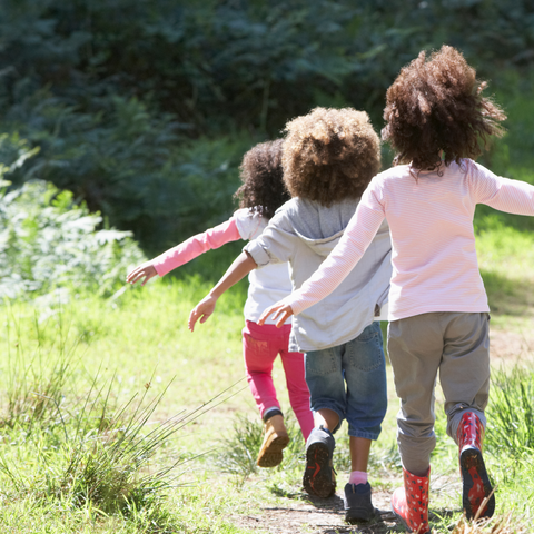 three mixed race children running with their arms stretch out