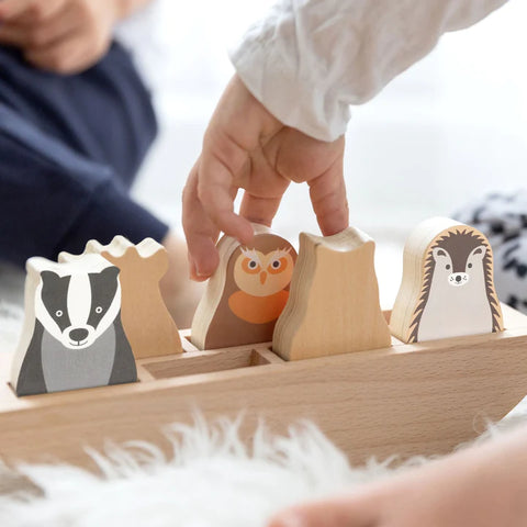 child playing with rosa and bo woodlies in a wooden boat