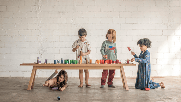 four young children playing with grapat open ended wooden toys on a light wooden table