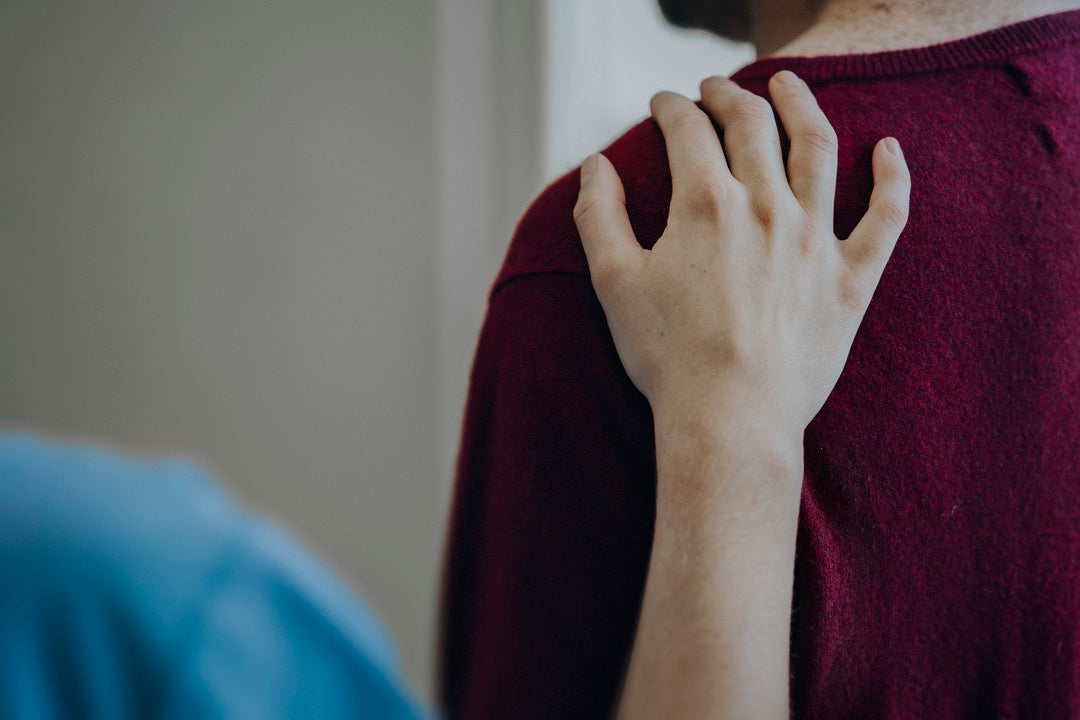 Nurse with hand resting on a patient's shoulder in hospital