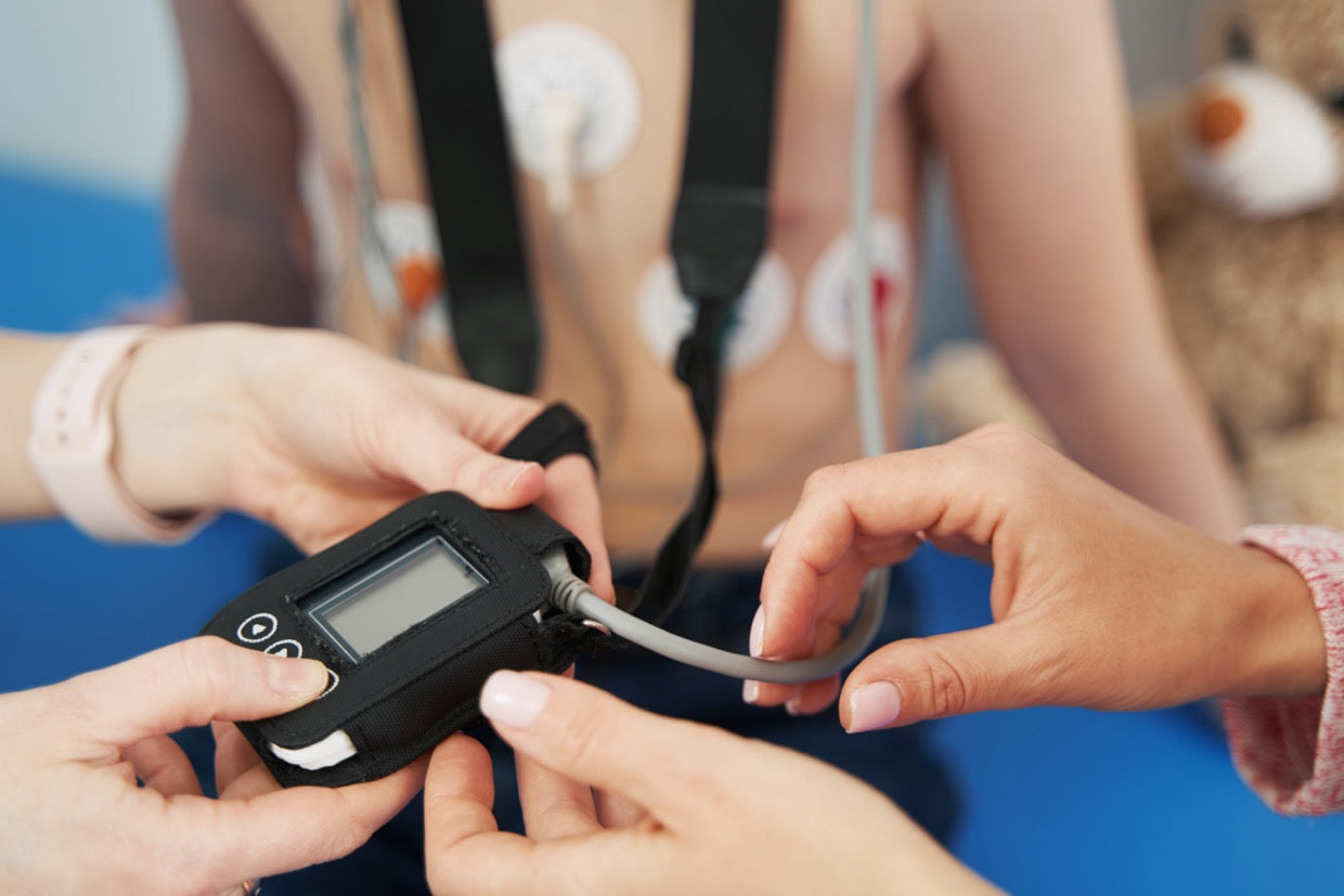 Doctor showing Holter ECG monitor to patient in pediatric clinic