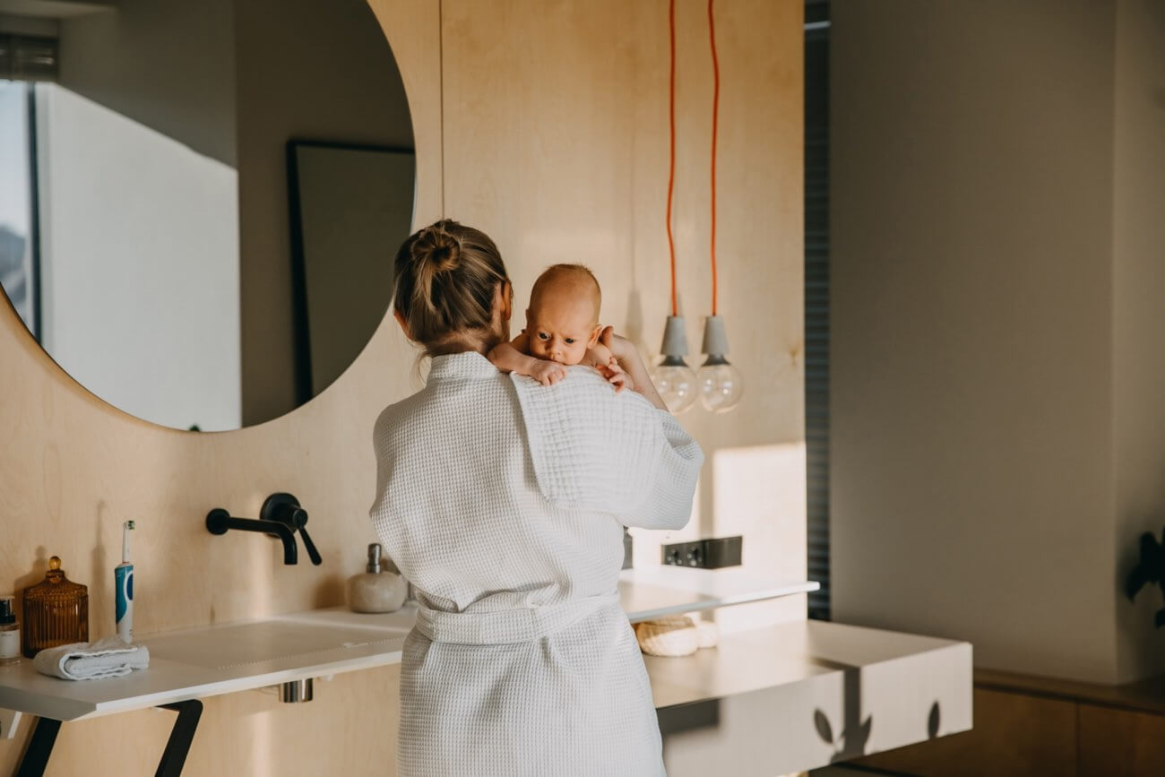 Mother holding newborn on shoulder, with cloth to burp baby.