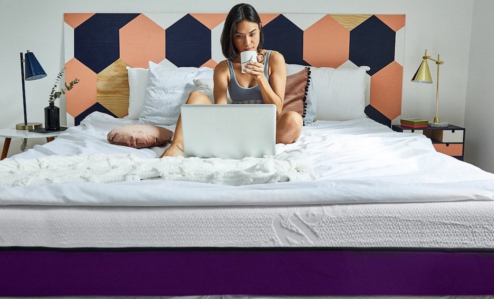 A woman drinks tea on her Polysleep foam mattress while browsing the computer