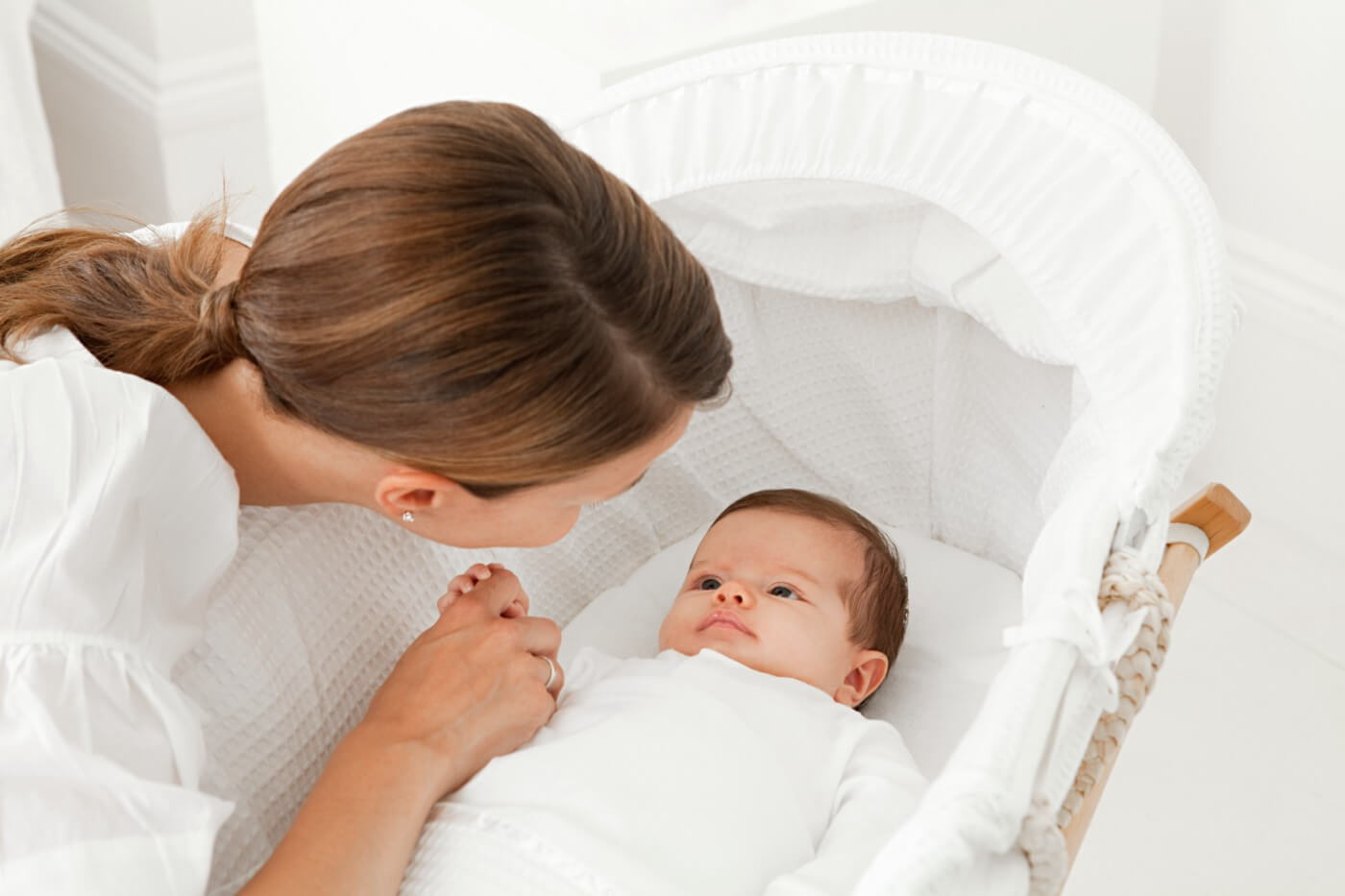 a mother comforts her baby in the bassinet