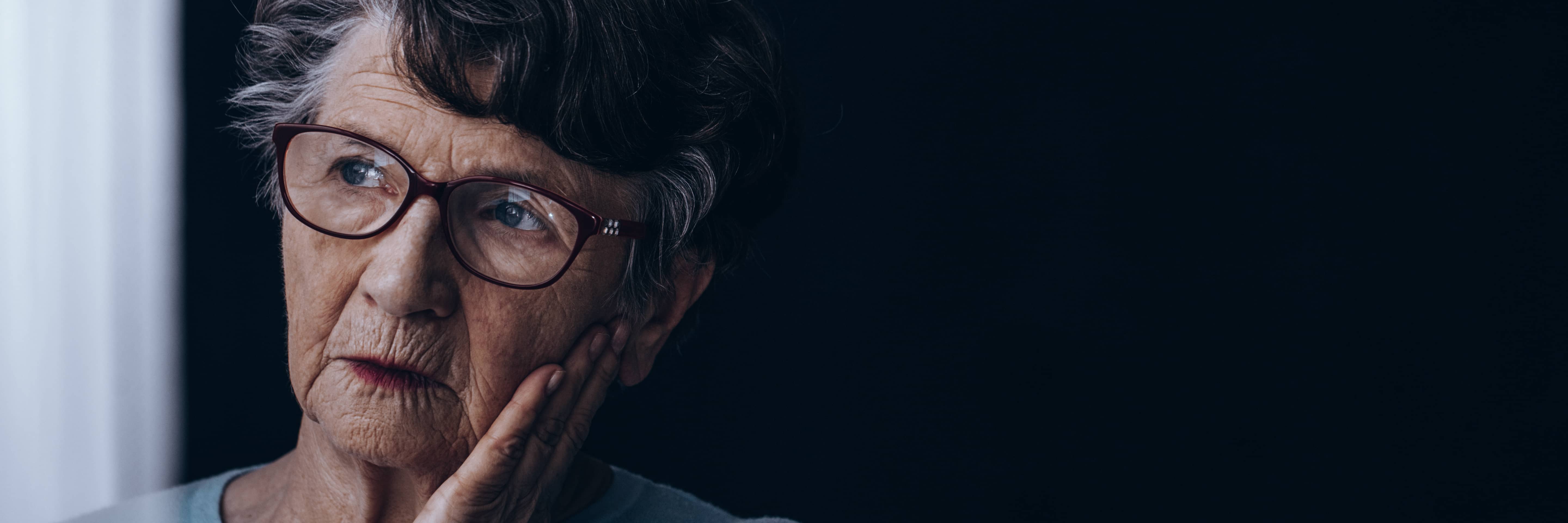 Elderly woman, alone, looking thoughtfully by a window