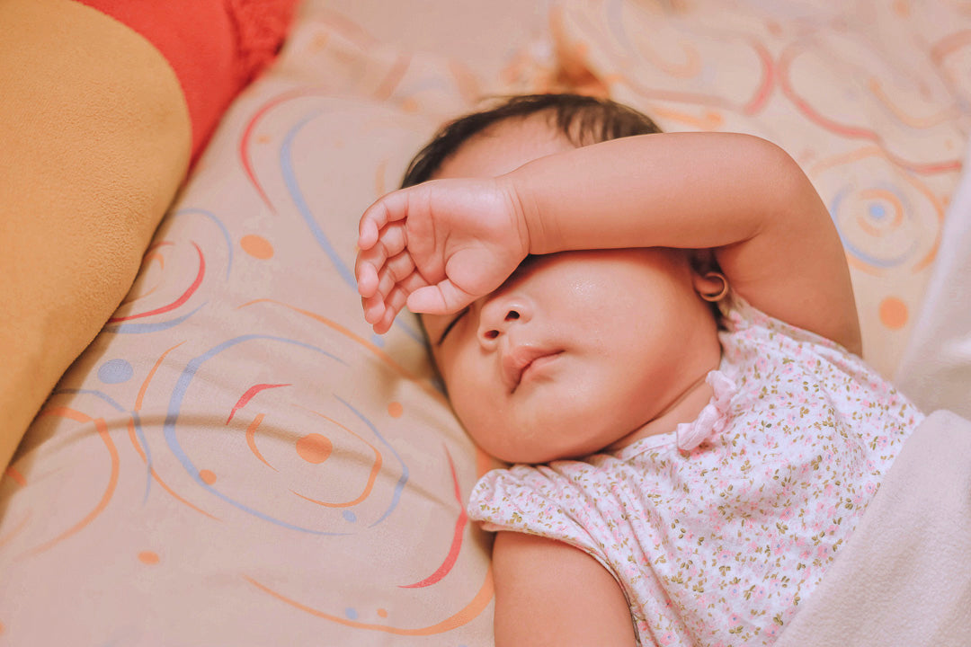 a baby sleeping with one arm over the face