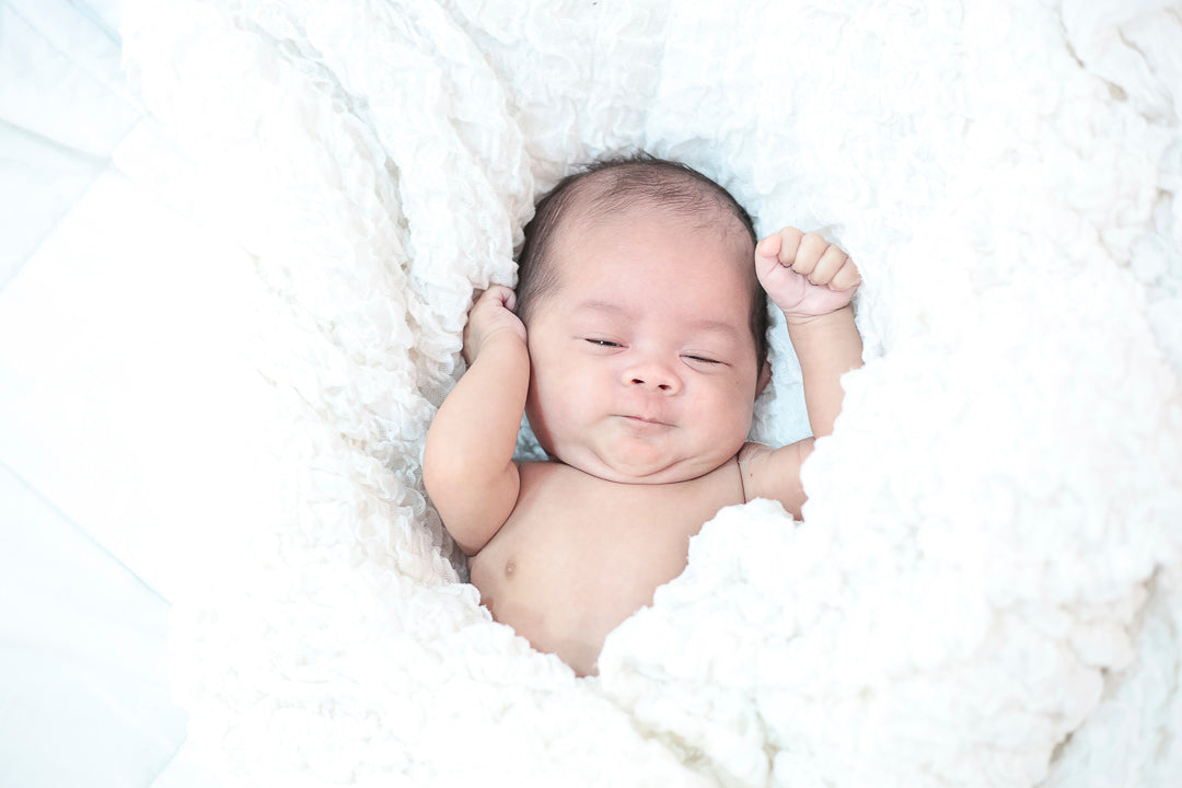 un bébé qui dort dans des draps blancs