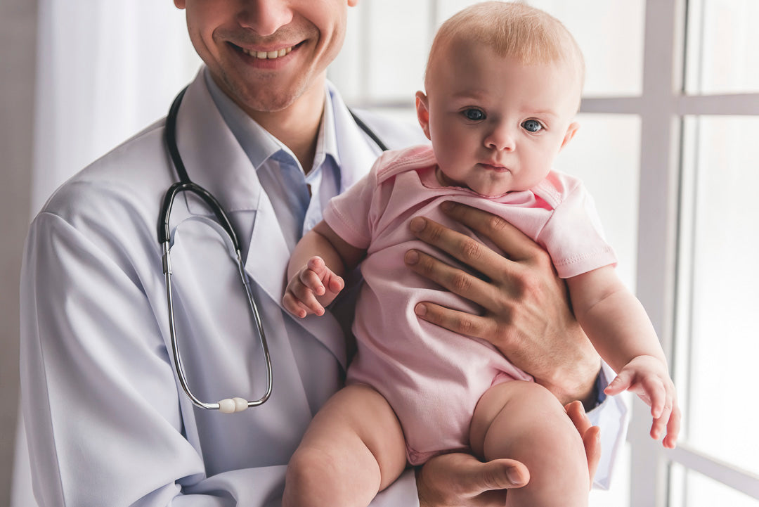 a baby held in the arms of a doctor