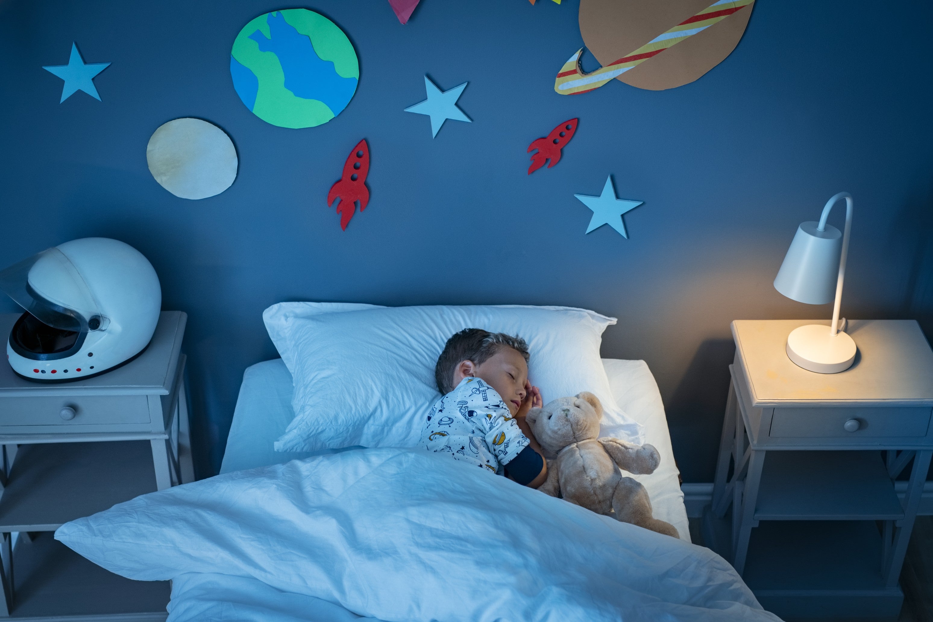 Young boy asleep in his bed with a light on
