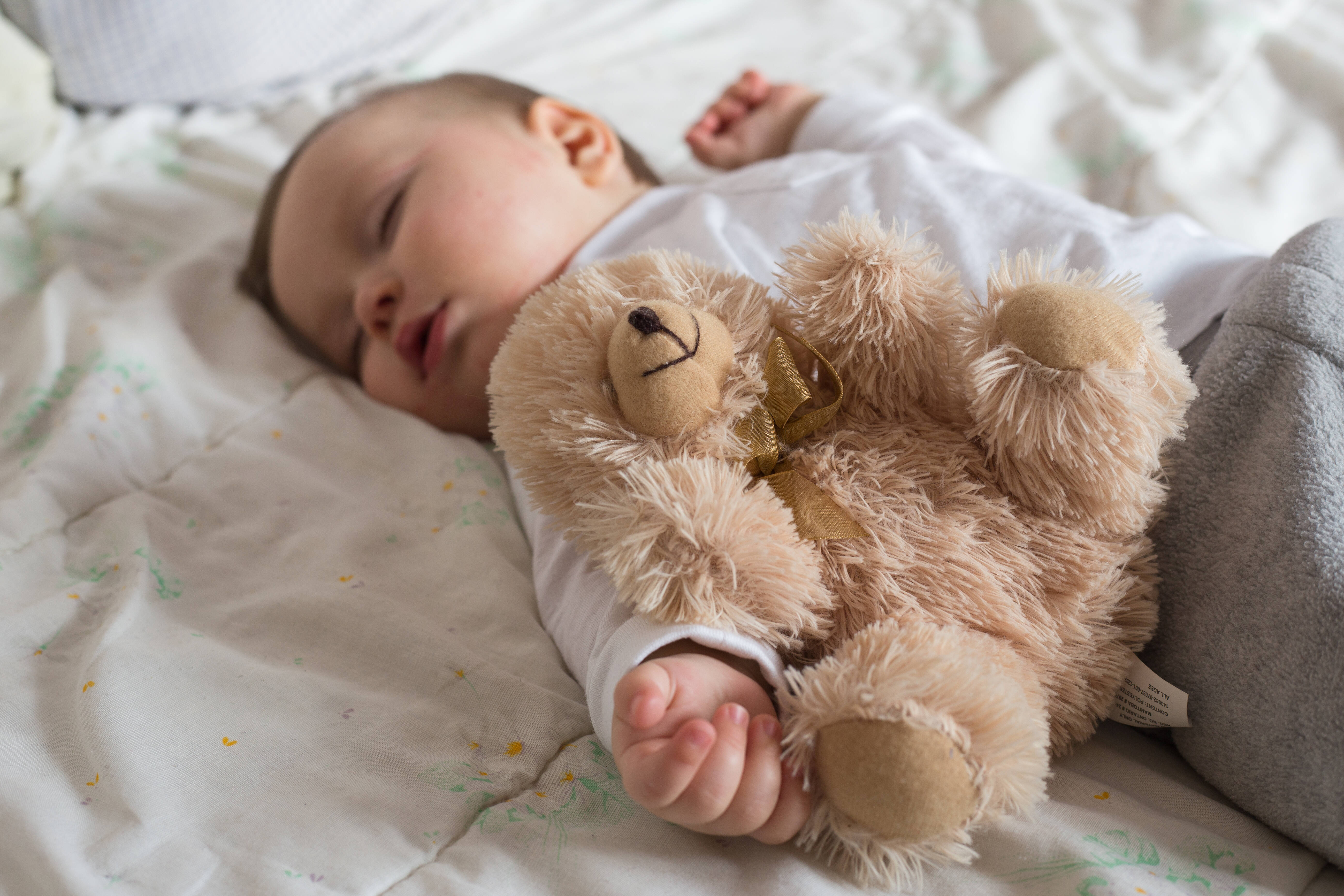 Baby sleeping in bed with a teddy bear