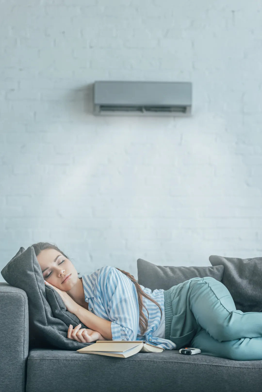 A woman sleeping on a sofa in a room with air conditioning.