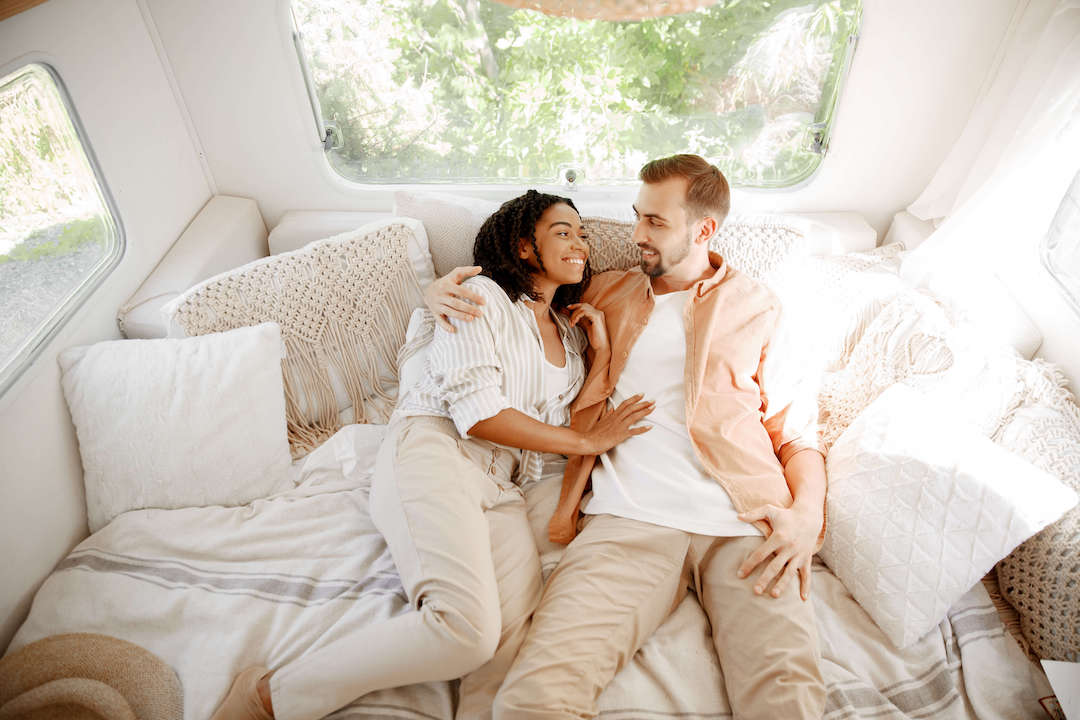 A smiling couple lying on their trailer bed