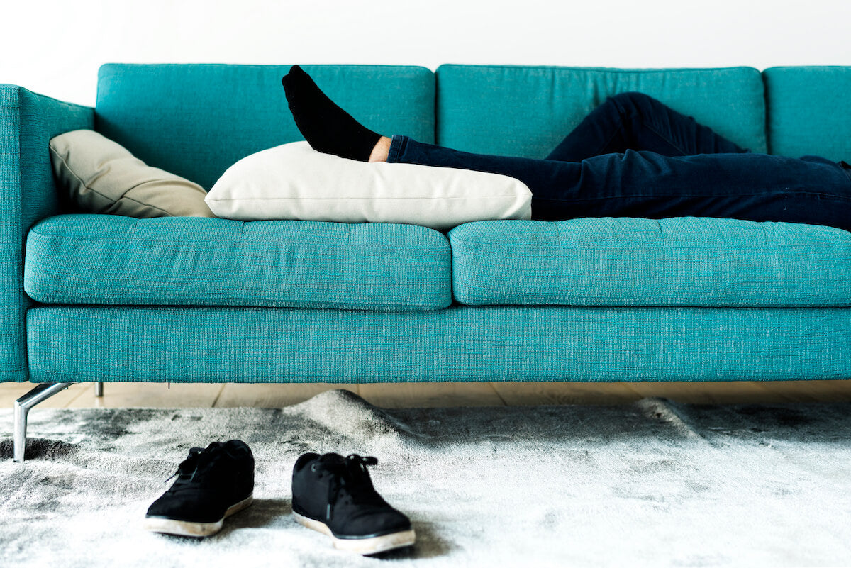 A man lying on a sofa with his legs low on the pillow