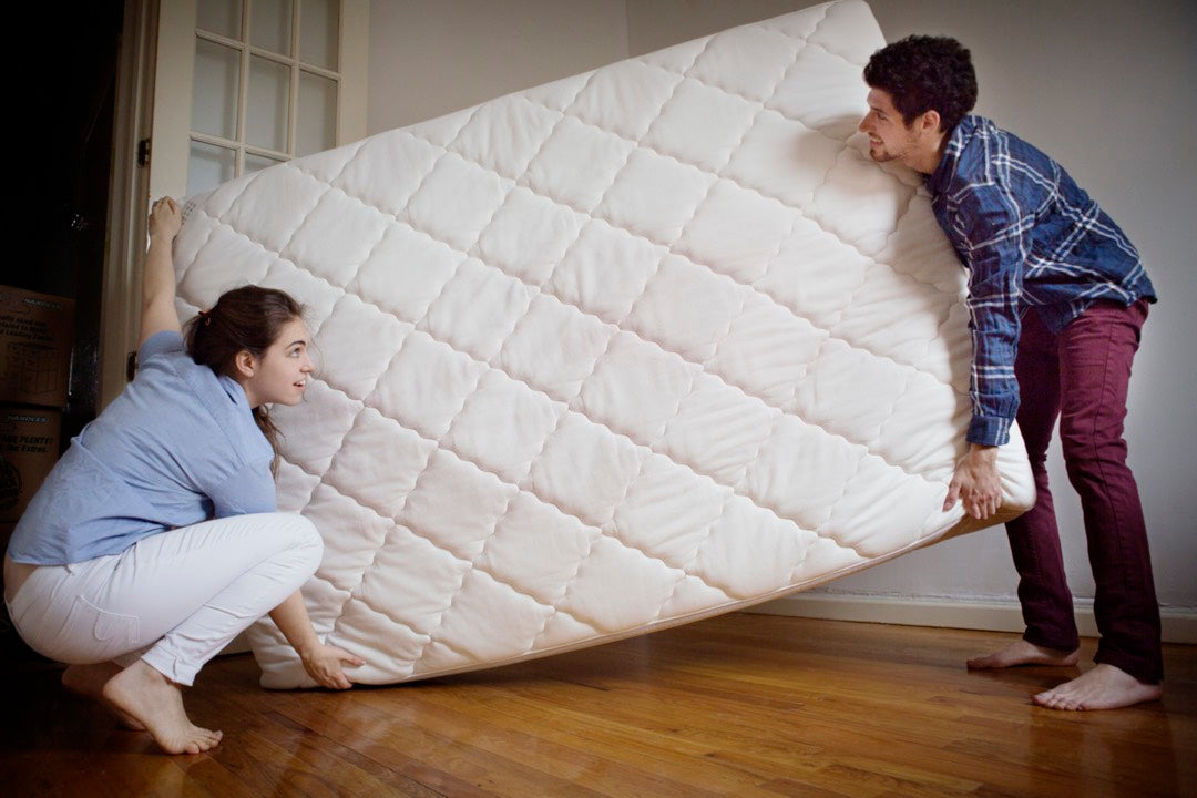 A couple carrying a mattress in order to replace it.