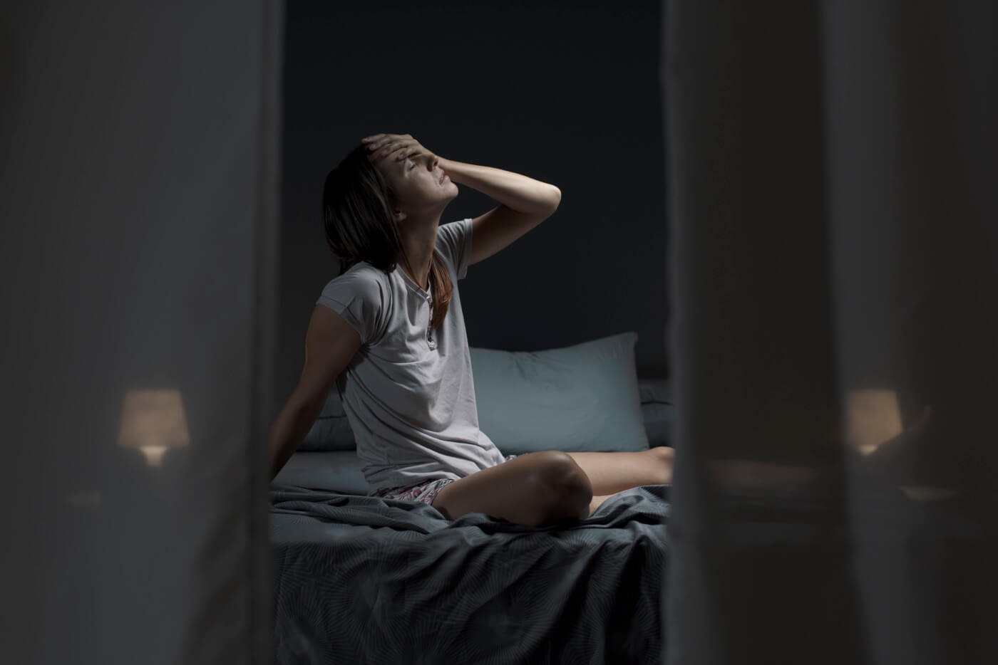 Woman having night sweats sitting in bed