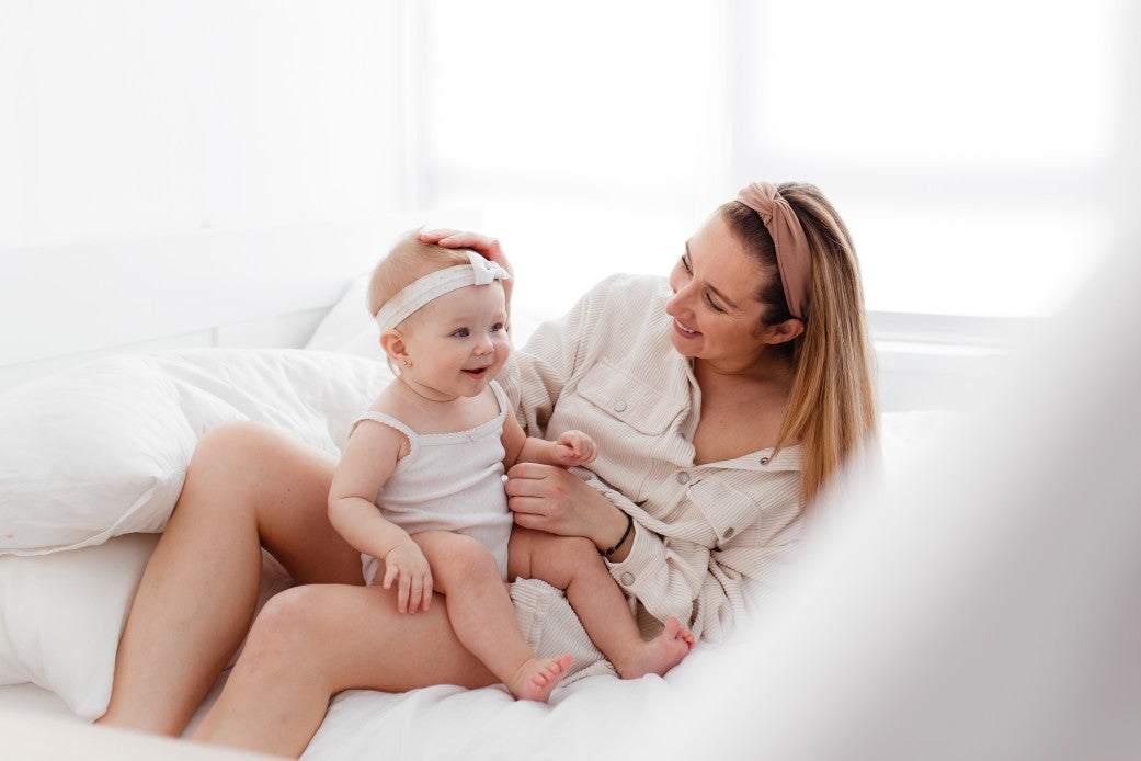 Mom playing with baby girl on the bed in perfect environment
