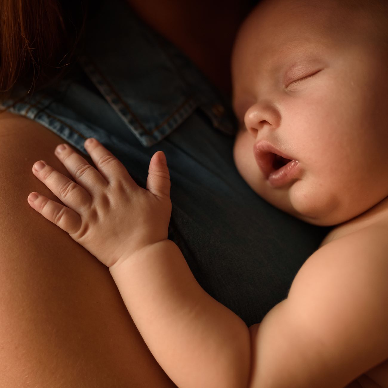 Close-up of a sleeping baby in his mother's arms.