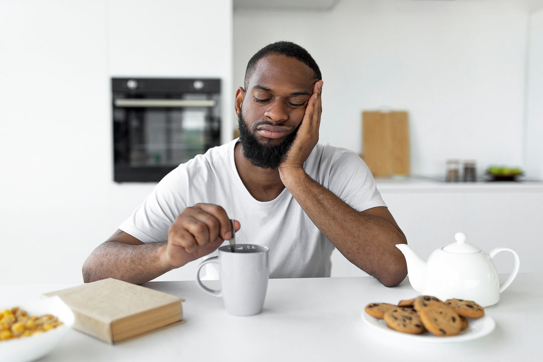 A man very tired sitting at a table in the morning