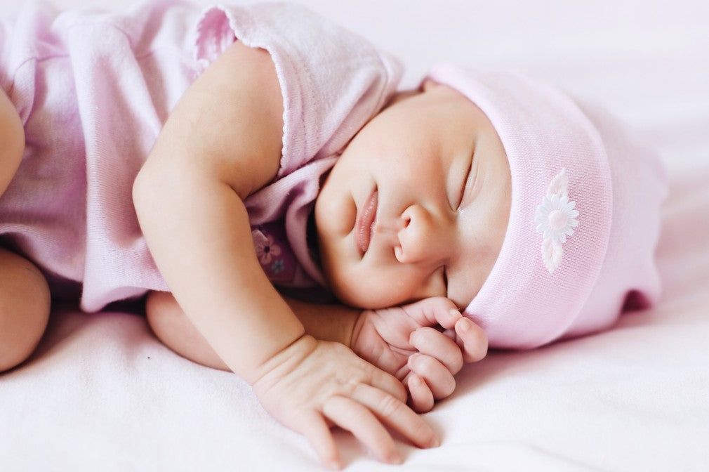 Baby sleeping aside dressed in pink pajamas