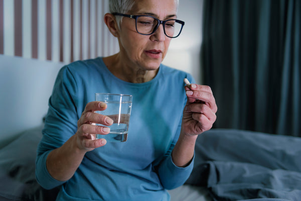 sleepless senior woman suffering from insomnia holding glass of water