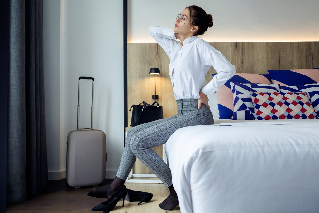 Young businesswoman with back pain sitting at the edge of her mattress