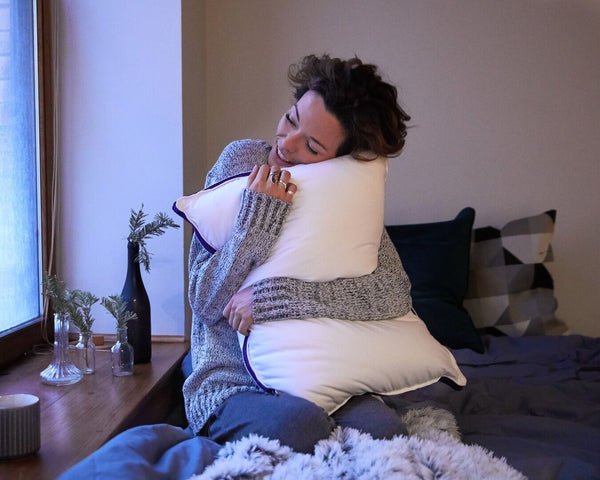Une femme fait un câlin à son Oreiller Polysleep sur son lit