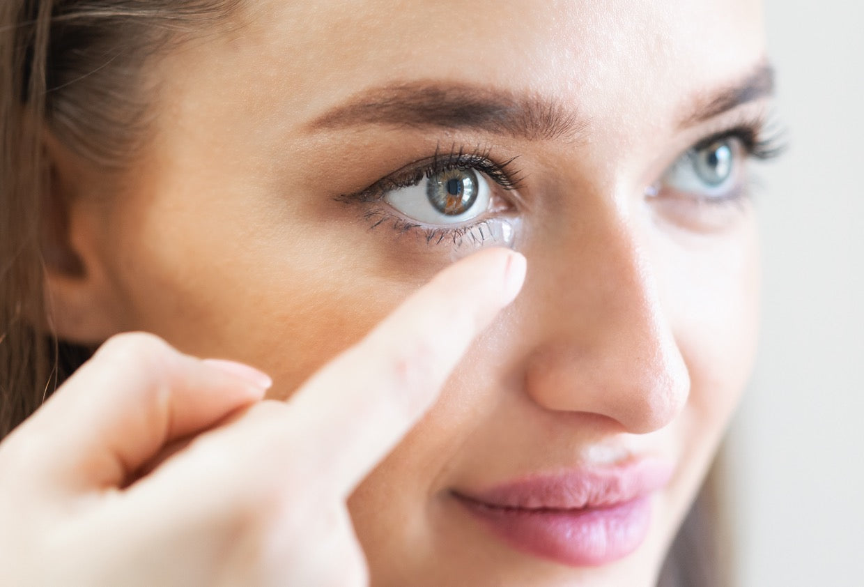 Close-up portrait of a woman applying her lens to her eye.