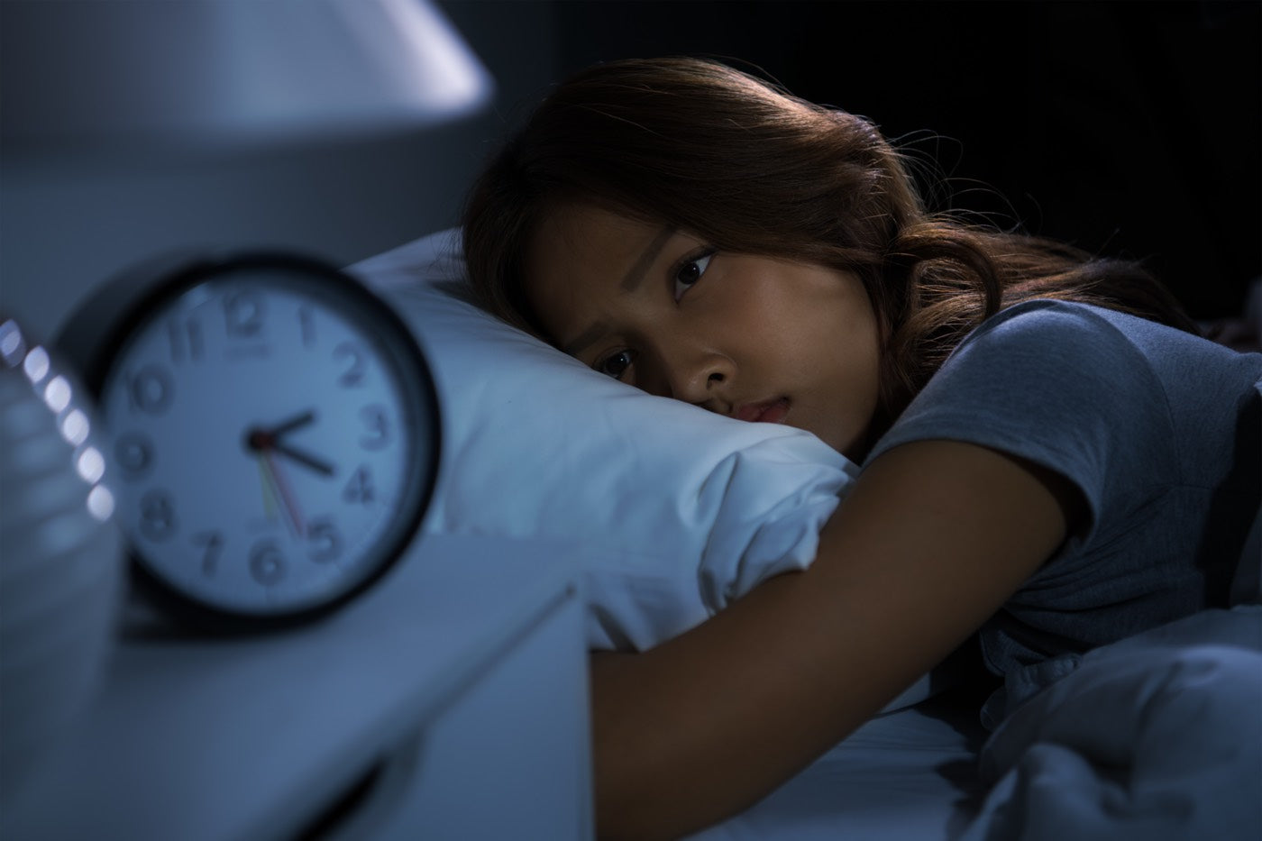 Insomniac woman observing the time from her dial in bed