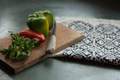 Hand-Printed Linen Tea Towel on a green slate countertop, with cutting board and knife, fresh basil and tomato