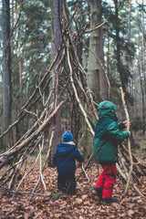 Children are playing outside, building a shelter with sticks