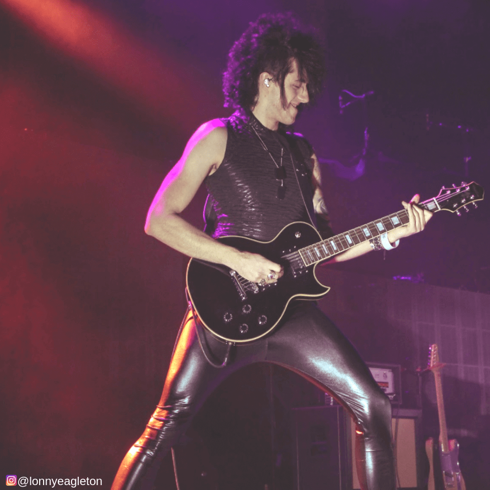 musician playing guitar in fake leather black tights