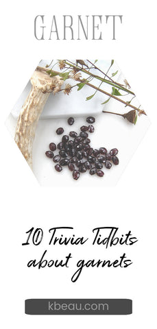 several rough faceted garnets on white background with antler and dried flowers