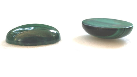 side view of two malachite cabochons on white background