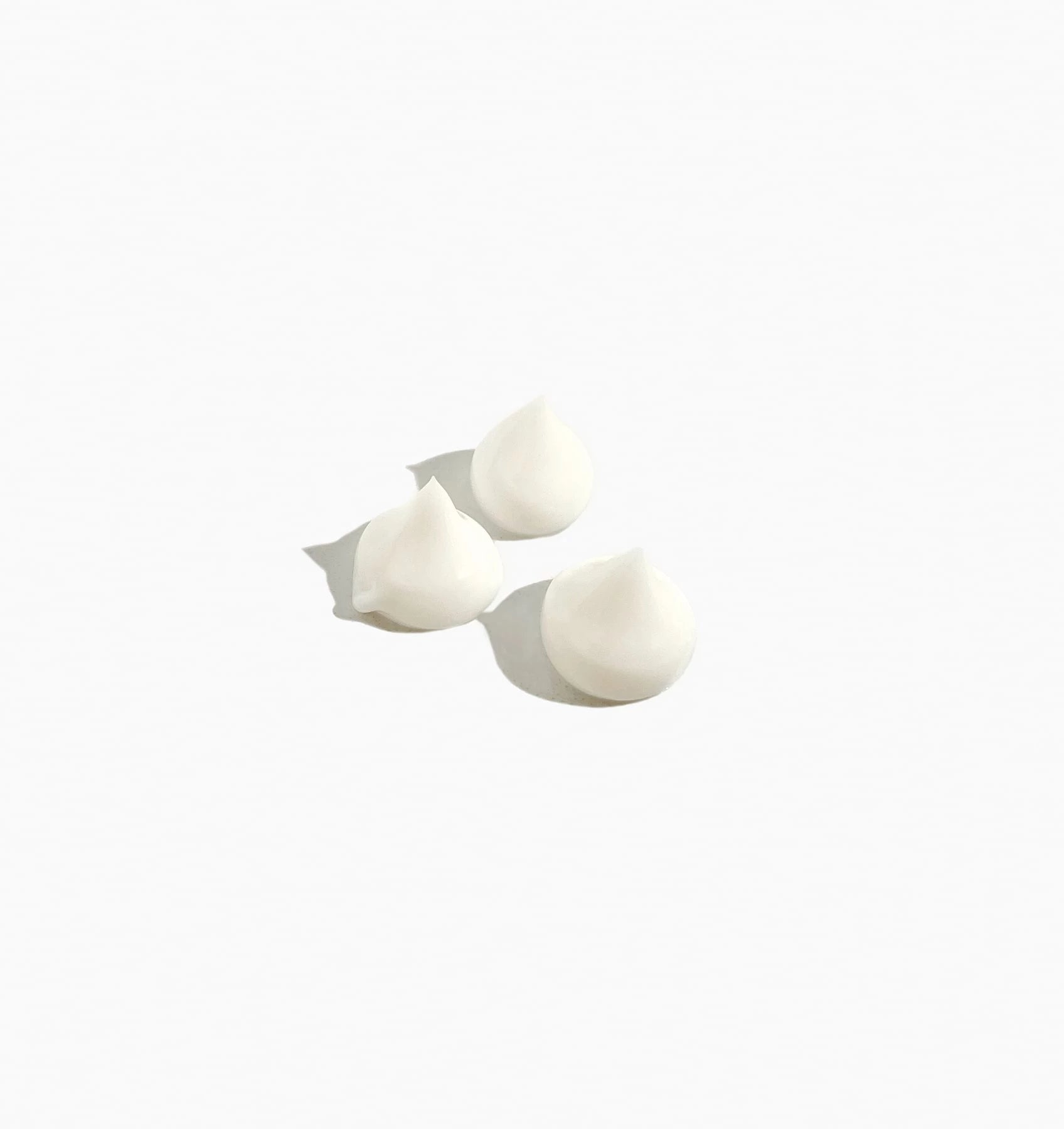 Three white meringue kisses on a light background.