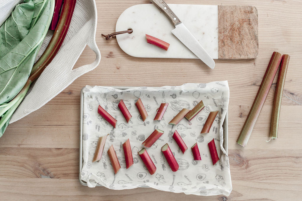 cookie sheet with large rectangle abeego on top and small chunks of rhubarb spread across the top