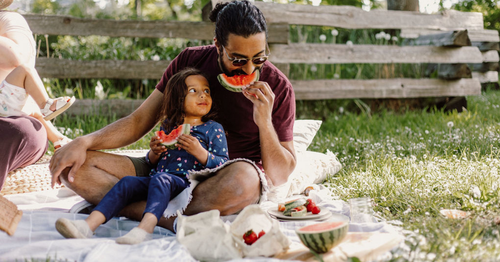 father and daughter eating watermelon together on a picnic