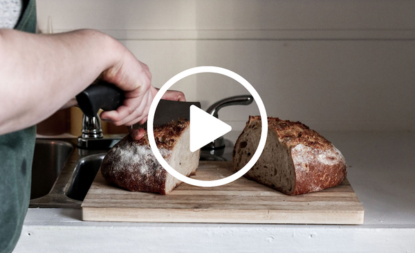 Hands slicing a loaf of bread with a play button on top