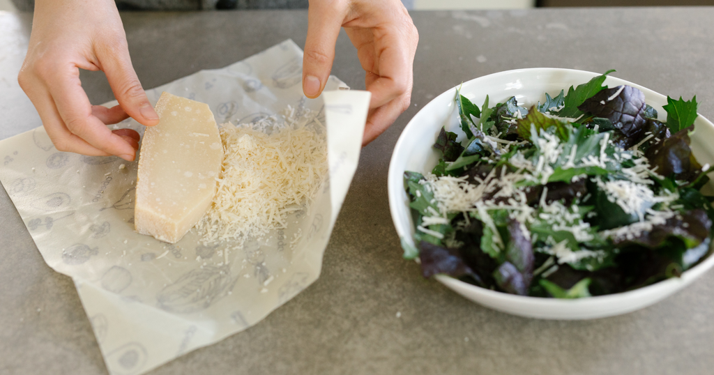 parmesan being unwrapped from Abeego to sprinkle atop a salad