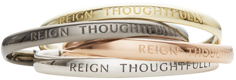 Stack of engraved "Reign Thoughtfully" cuff bracelets in 4 precious metal shades